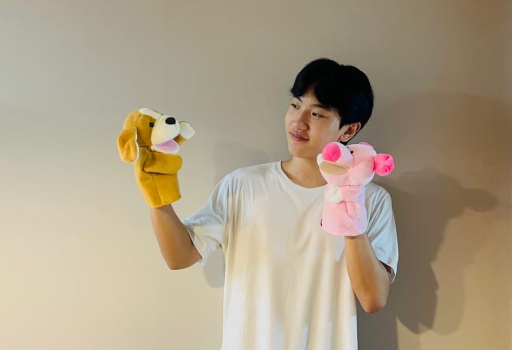 수업에 쓰는 손 인형 두 개를 들고 있는 청년 봉사자
